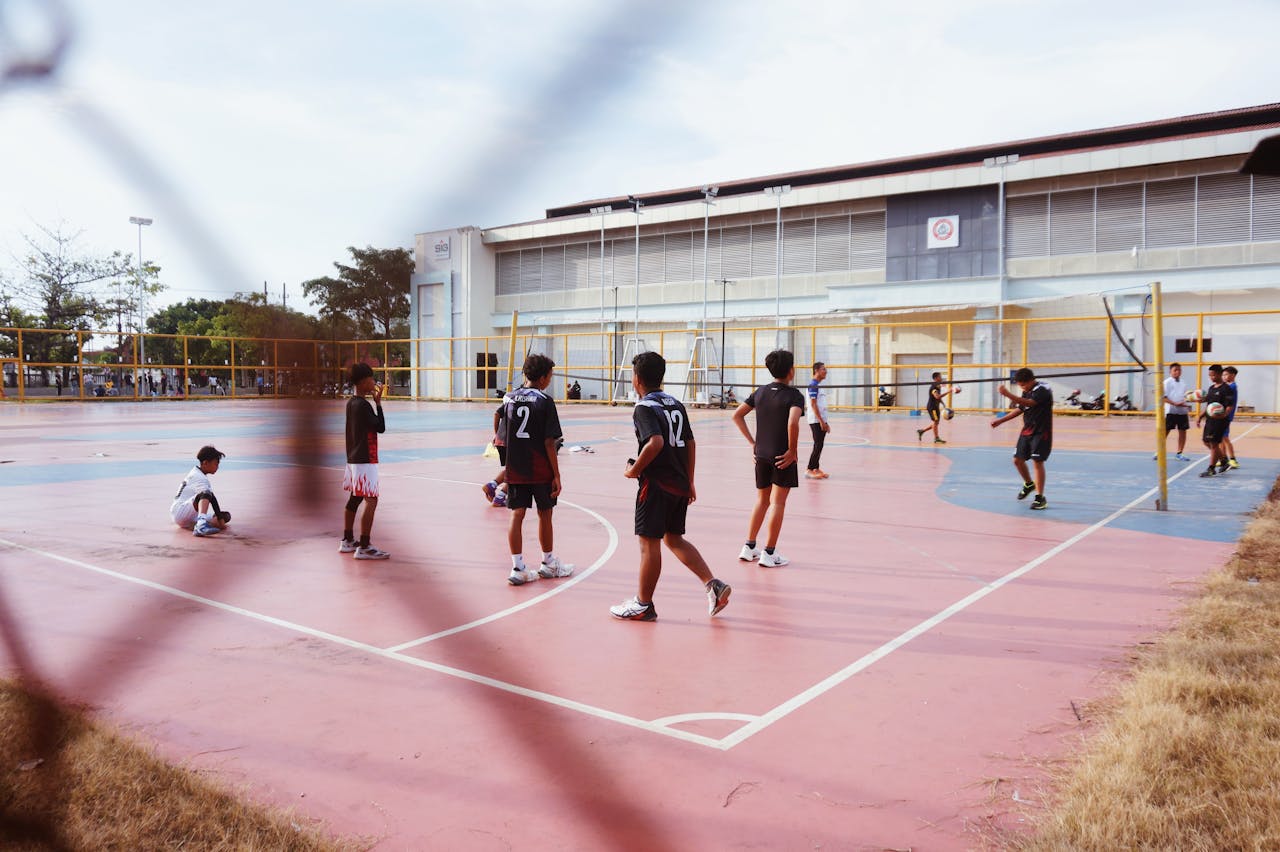 Group of teenagers playing volleyball on an outdoor court in Jawa Timur, Indonesia.