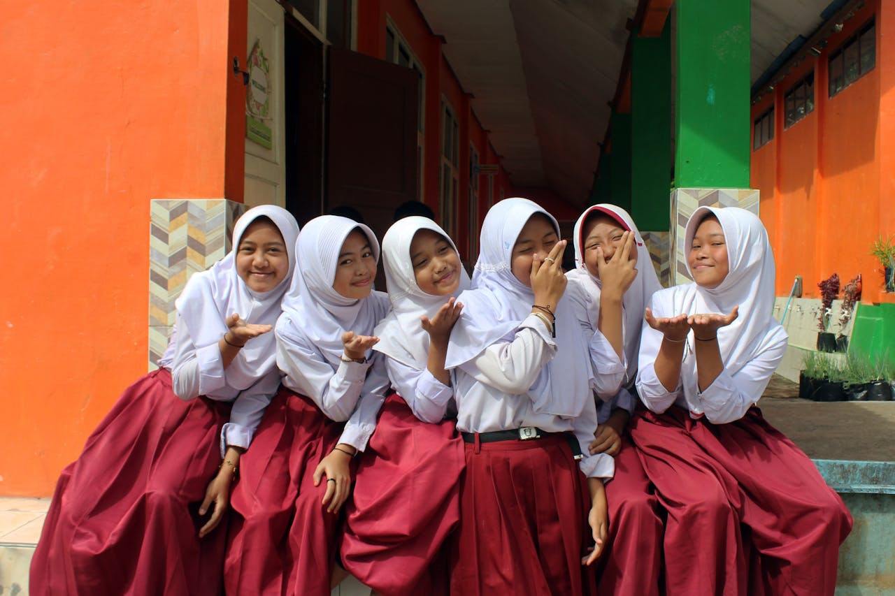 A joyful group of Indonesian schoolgirls in traditional uniforms during a sunny day.