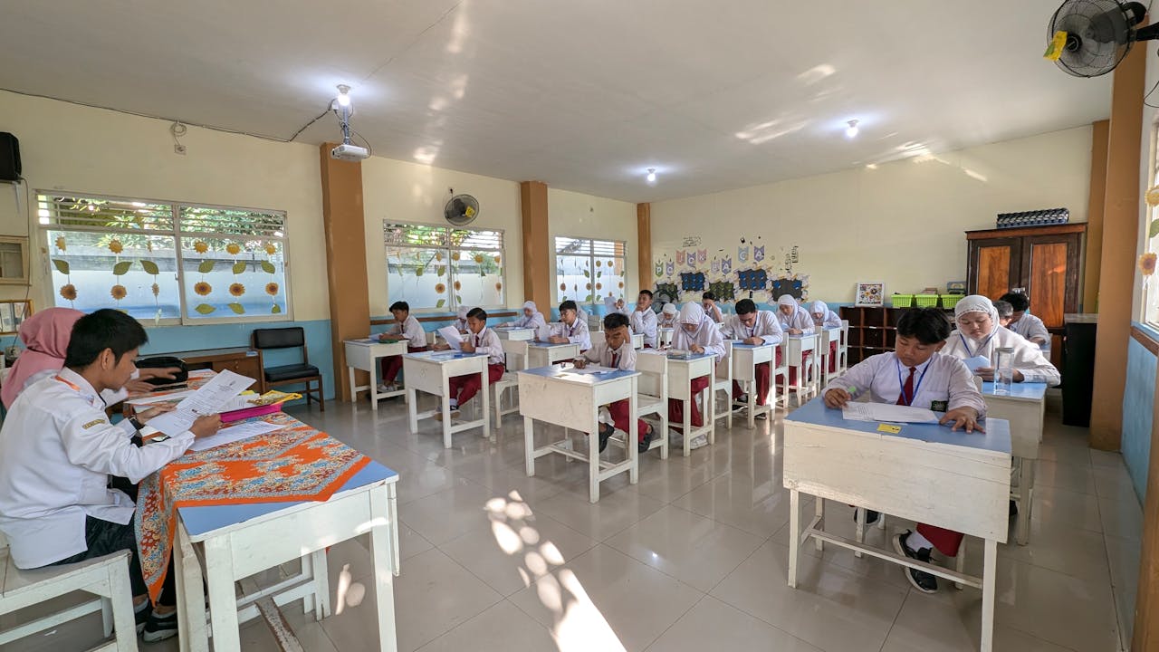 Students in an Indonesian classroom taking an exam under natural lighting.
